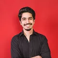 A man with a mustache wearing a black shirt, looking directly at the camera with a neutral expression.
