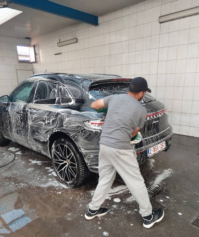 Two men are repairing a car together in a well-lit garage filled with tools and equipment